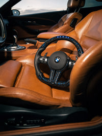 Volante BMW de fibra de carbono forjada con LED sobre el asiento de un BMW