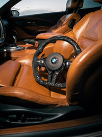 Volante BMW de fibra de carbono forjada negra sobre el asiento de un BMW