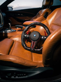 Volante BMW de fibra de carbono forjada roja sobre el asiento de un BMW