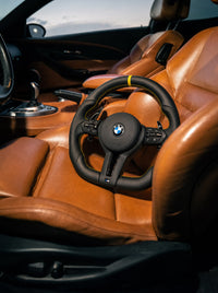 Volante BMW de cuero con franja amarilla sobre el asiento de un BMW