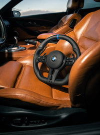Volante BMW de cuero con franja azul sobre el asiento de un BMW
