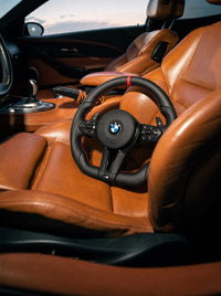 Volante BMW de cuero con franja roja sobre el asiento de un BMW