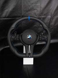 Volante BMW de cuero con franja y costura azules sobre peana