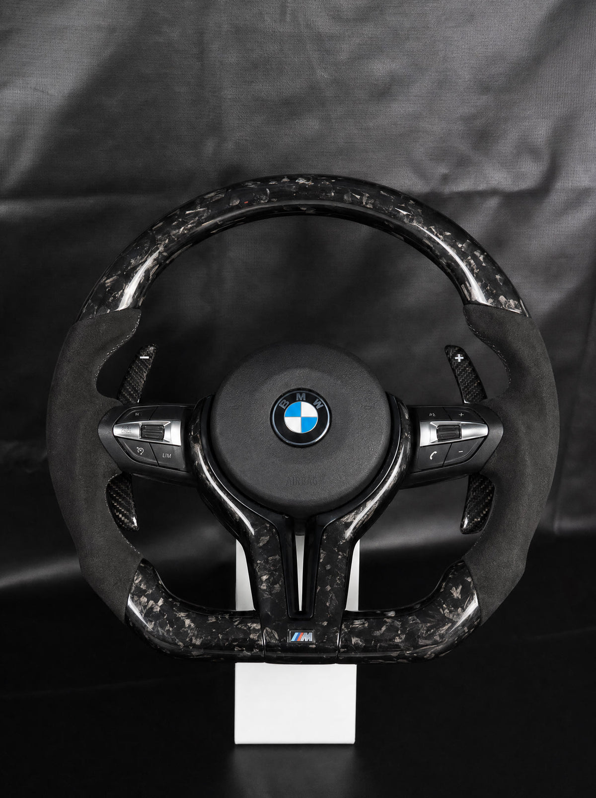 Volante BMW de fibra de carbono forjada negra sobre peana