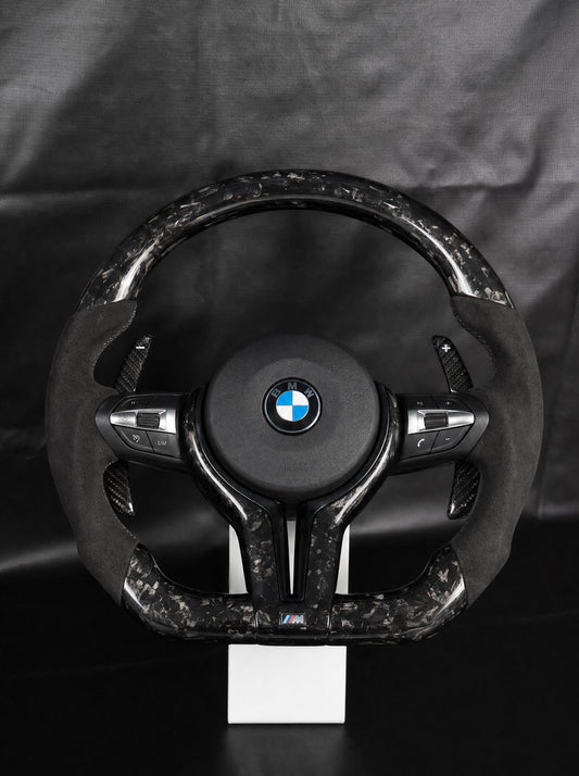 Volante BMW de fibra de carbono forjada negra sobre peana