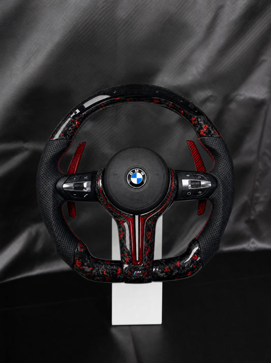 Volante BMW de fibra de carbono forjada roja con airbag sobre peana