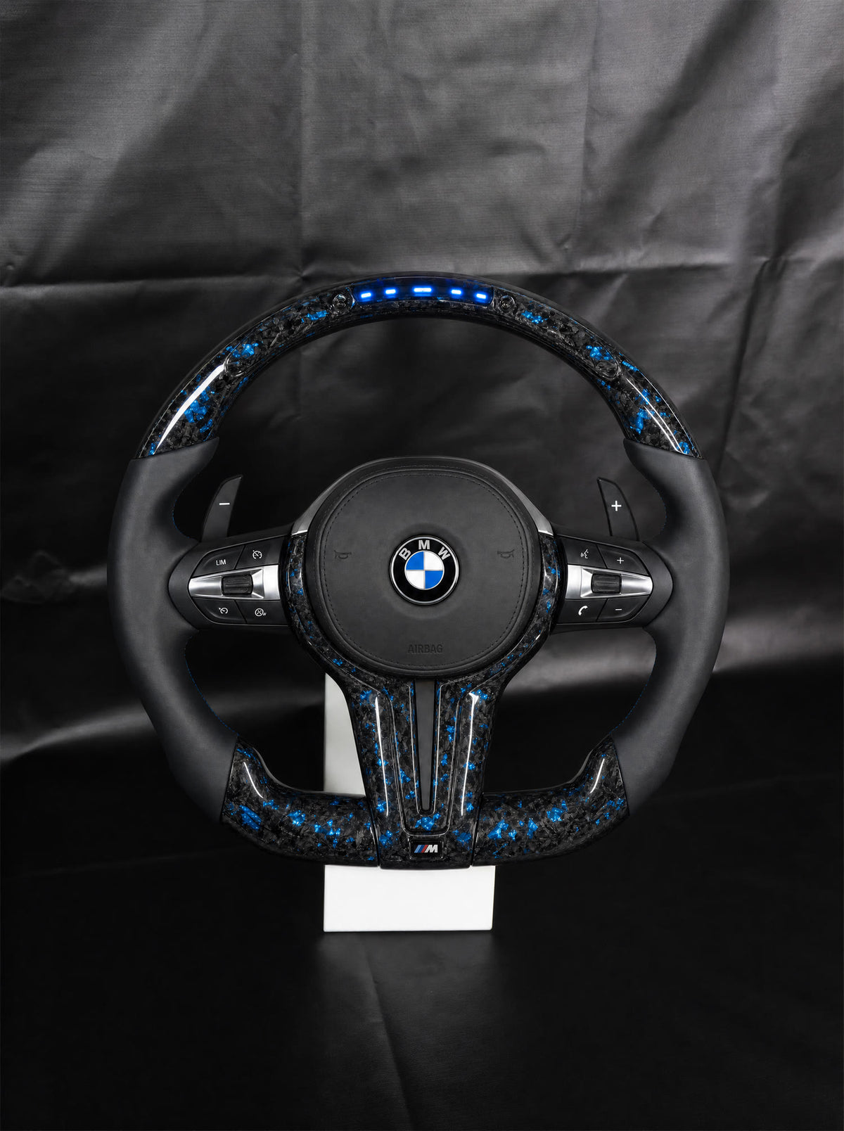 Volante BMW de fibra de carbono forjada con LED sobre peana
